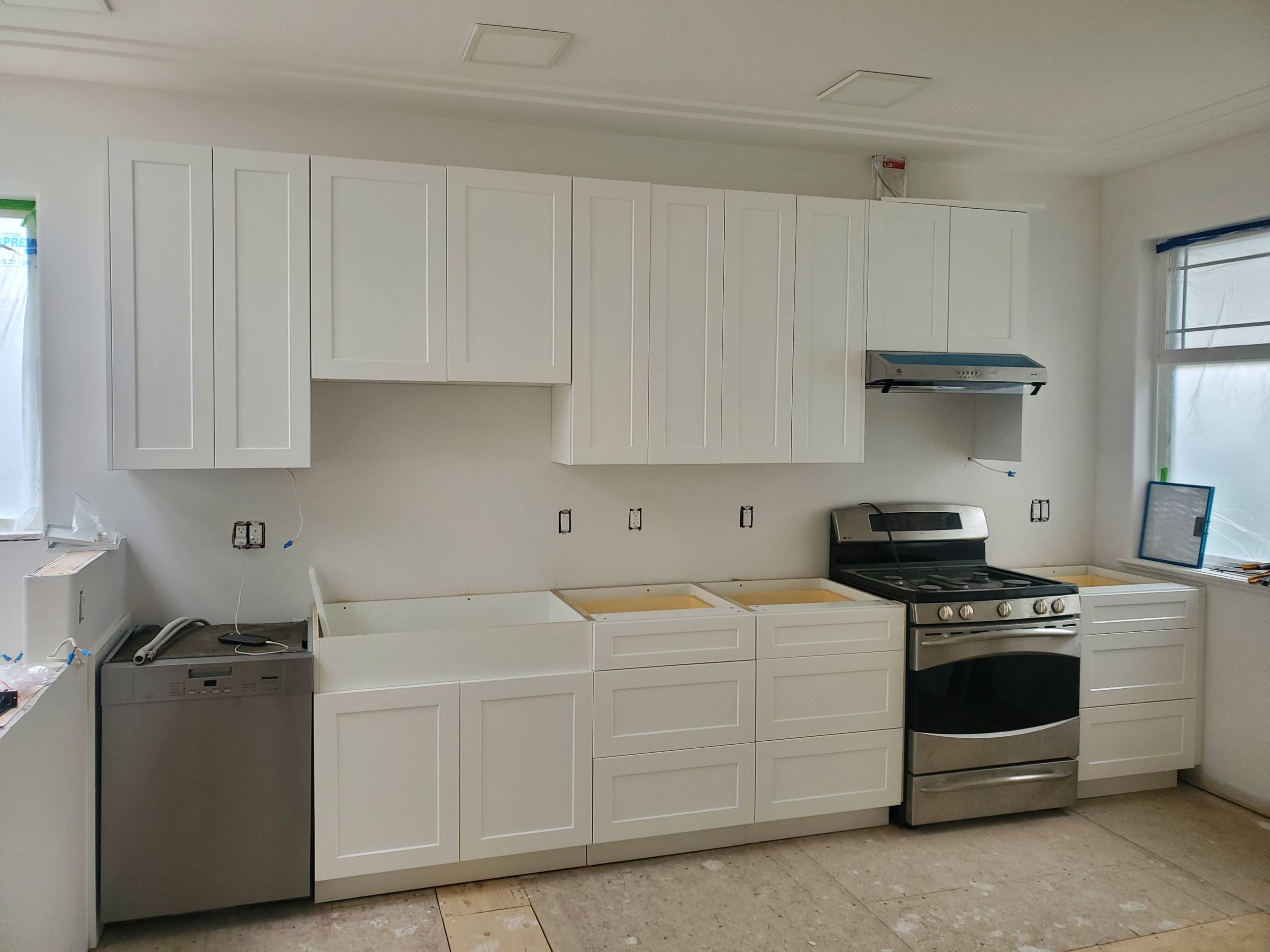 Kitchen renovation in progress with new white shaker cabinets installed before countertops